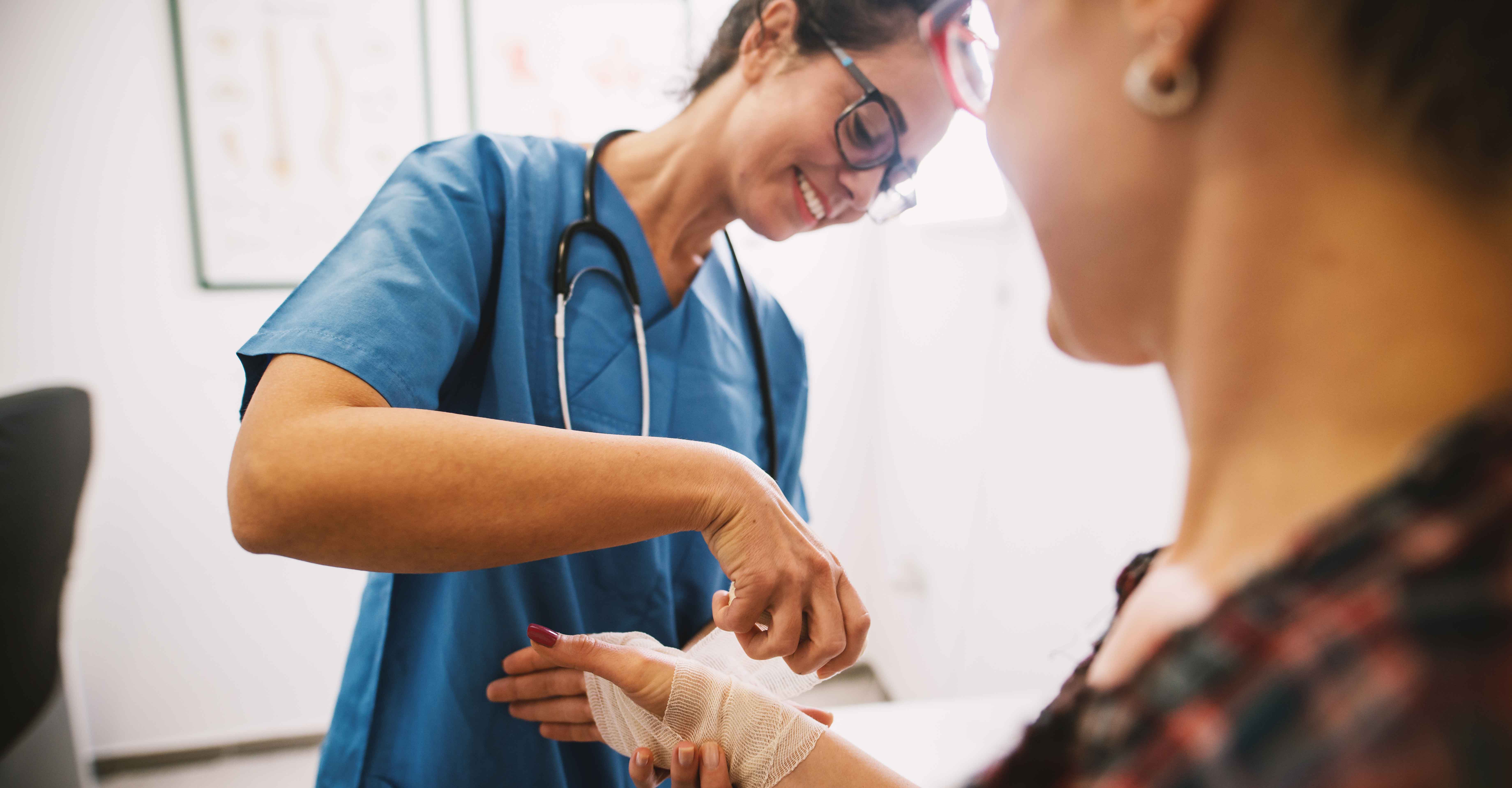 A nurse, who earned her wound care certification, bandages a patient's wound on her arm.