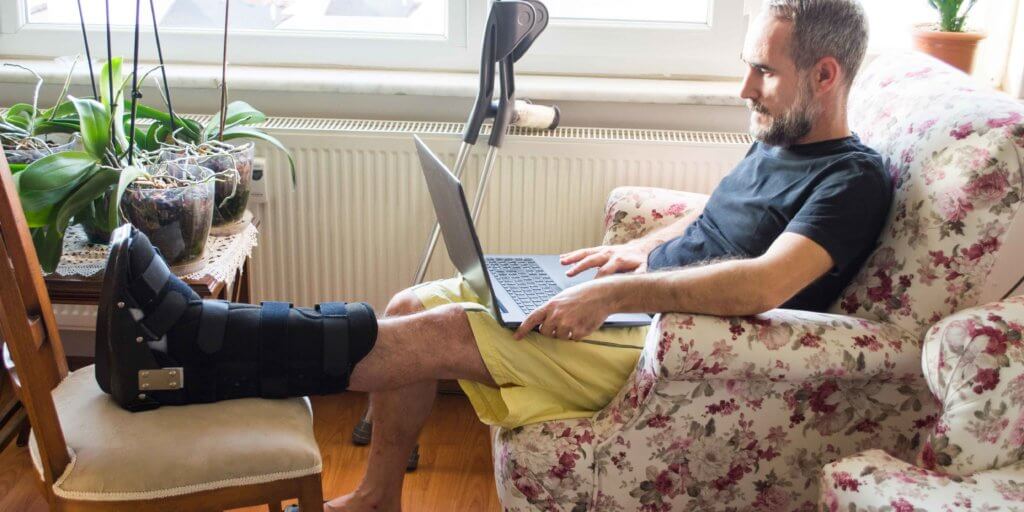 A man sits with his total contact cast elevated on a chair.
