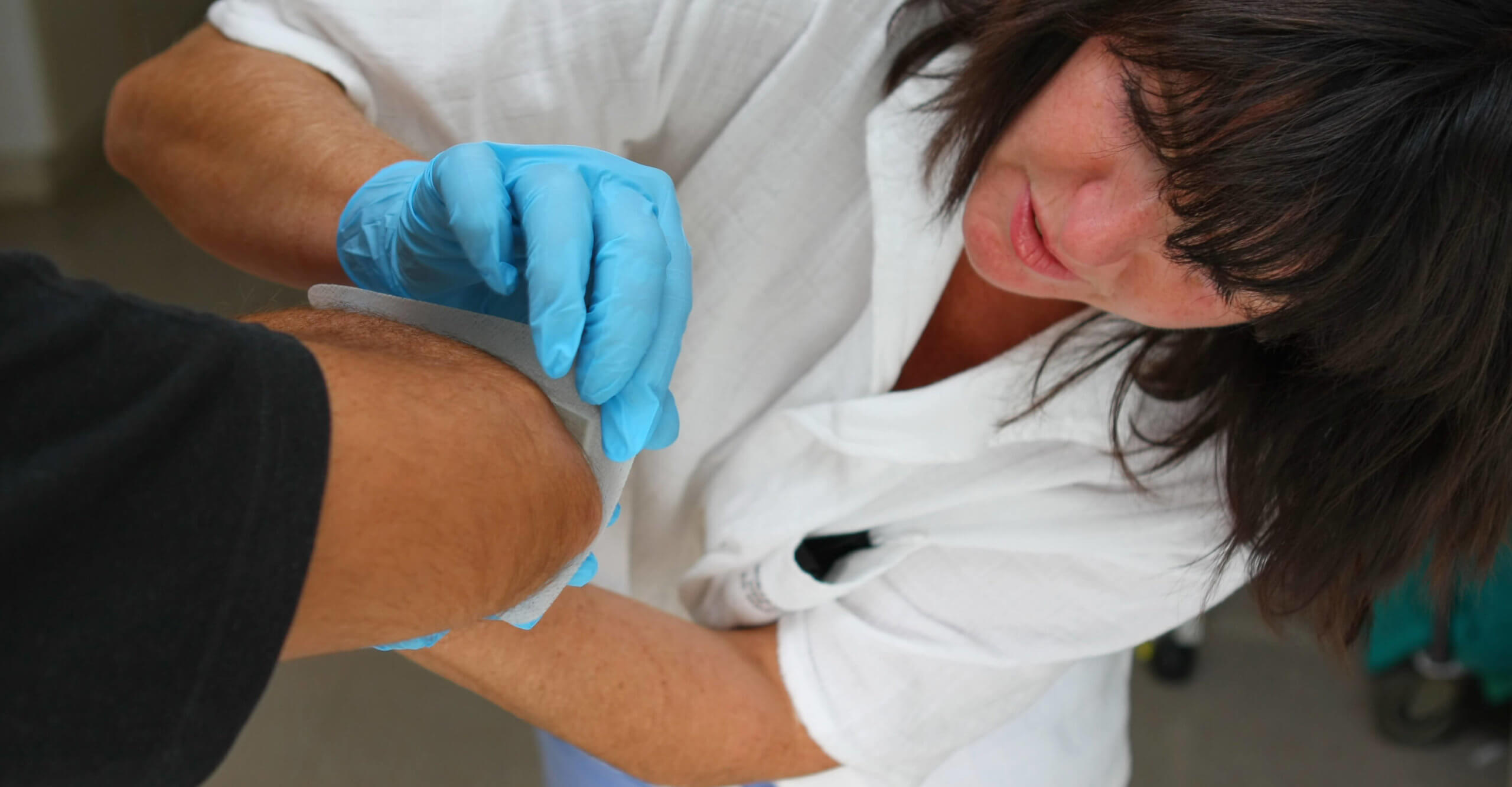 A nurse bandages a patient's knee wound.