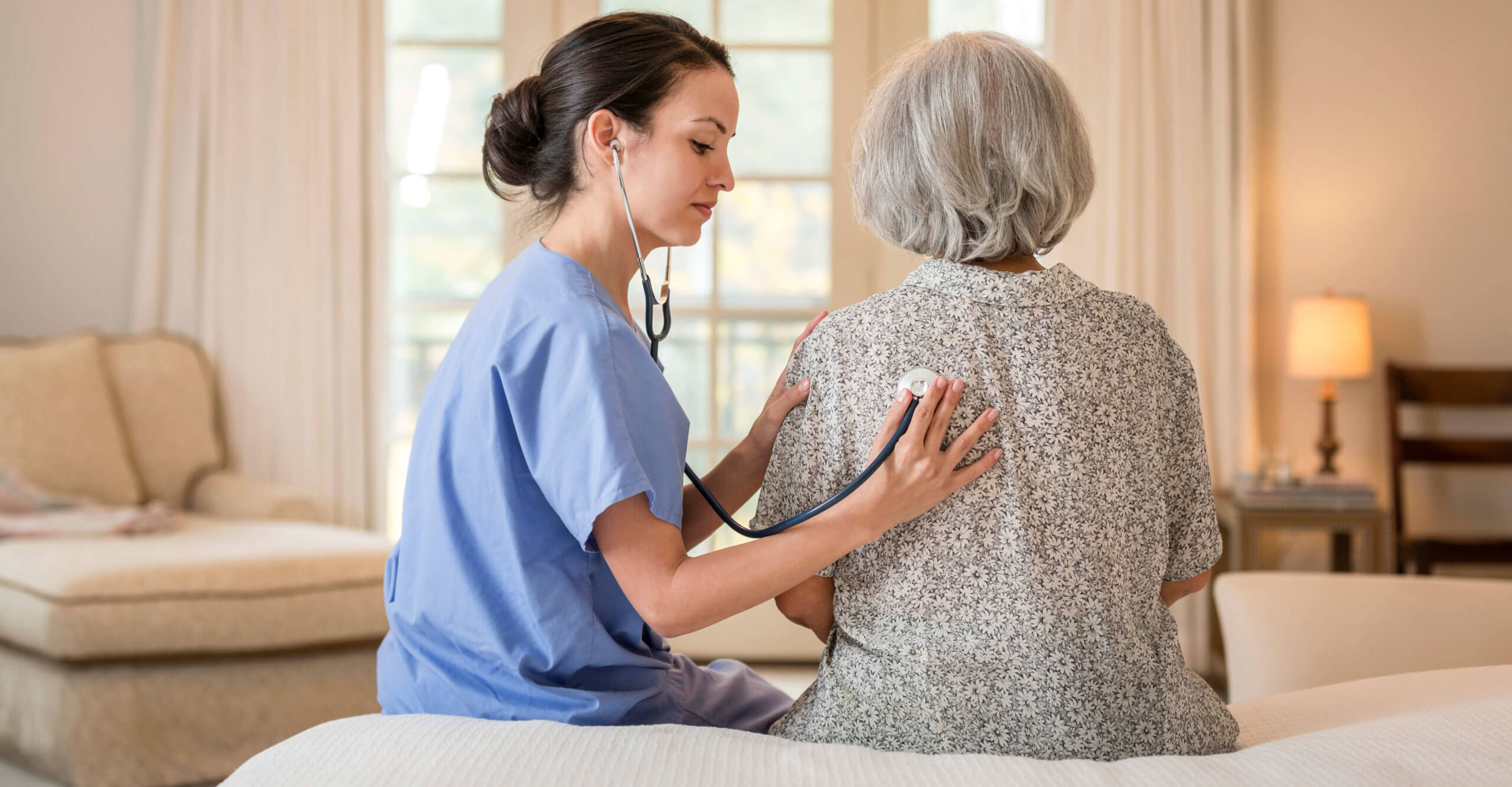 A nurse listens to the lungs of a senior home health patient.