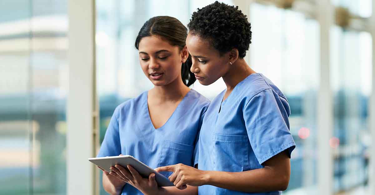 Two nurses reviewing a document on a tablet