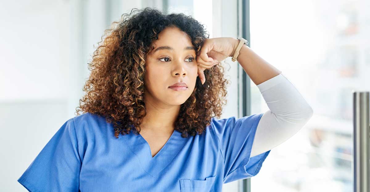 stressed nurse leans against window thinking and looking outside