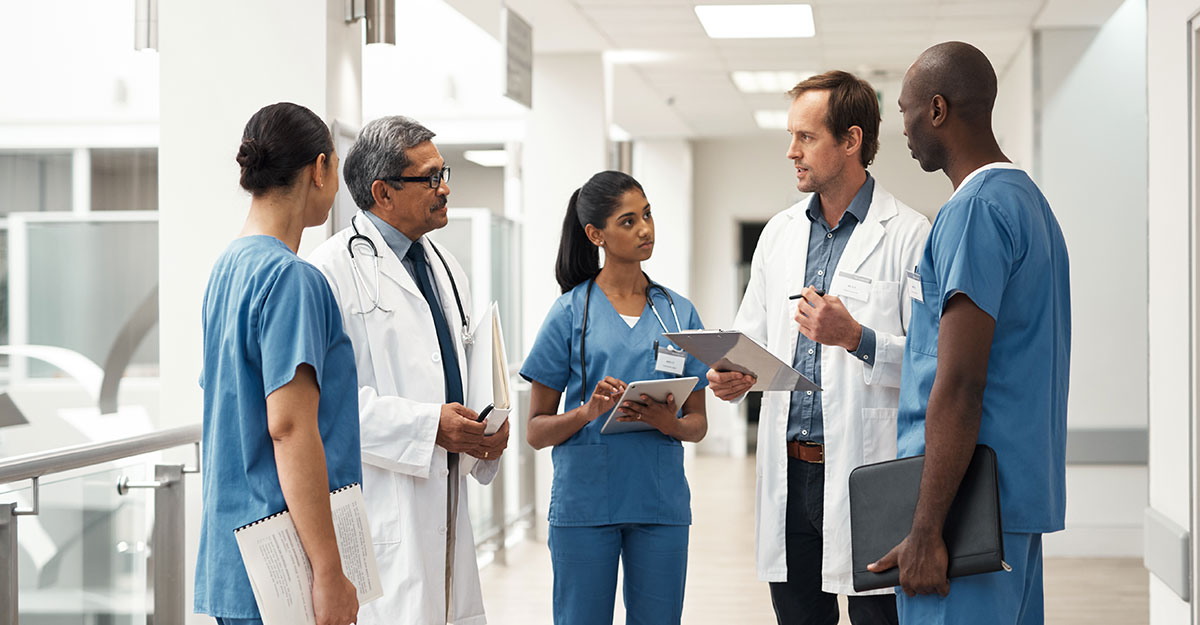 Collaboration in healthcare shown by healthcare professionals standing in a group talking