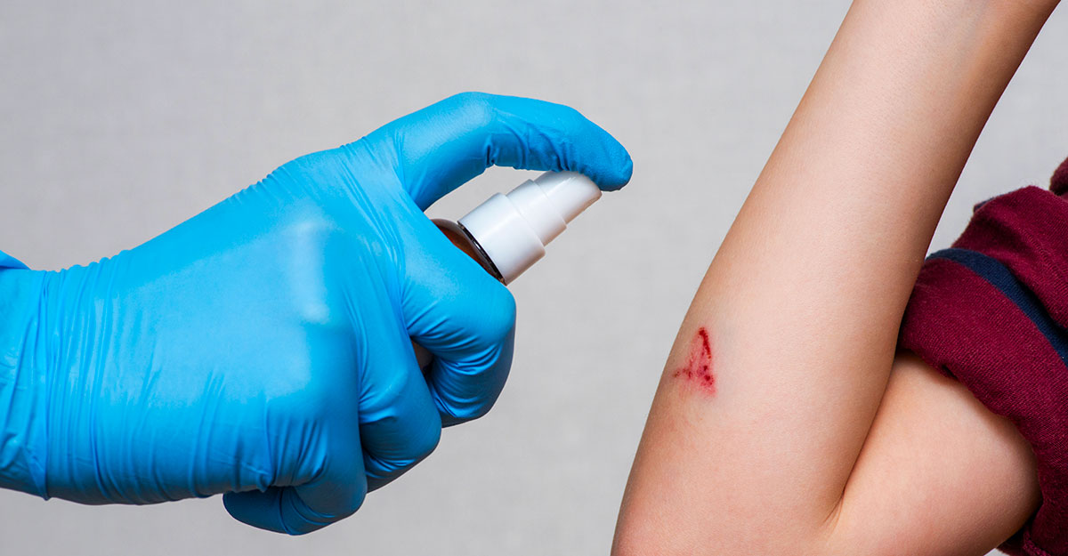 Person using wound care spray on a cut